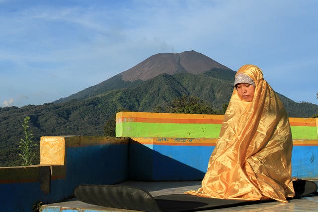 <p>File. A woman prays in Brebes town in Indonesia's Java province with Mount Slamet in the background</p>