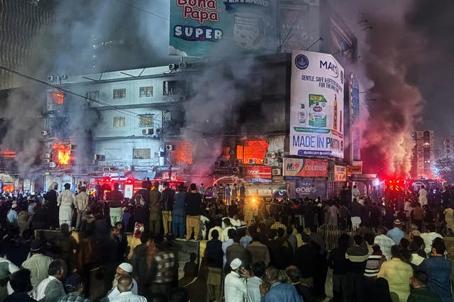 <p>People gather as firefighters try to control a massive fire that broke out in a multi-story shopping mall in Karachi, Pakistan, on Sunday, 18 January 2026</p>